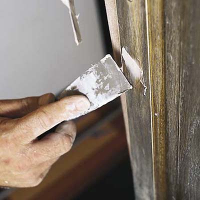 filling old screw holes with a filler applied with a putty knife 