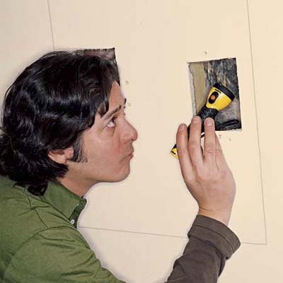 Inspecting the wall cavity with flashlight.