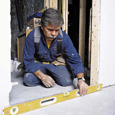 Tom Silva taking measurements while installing a prehung door