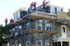 men on a scaffold working on a house's exterior