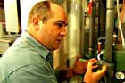 Richard Trethewey installing a weather-responsive heating control gauge to a boiler