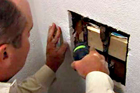 Richard Trethewey securing loose pipes behind a shower area
