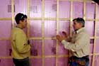 Tom Silva holding up an insulating panel in a basement corner wall