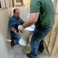 Richard Trethewey being handed a new toilet to install