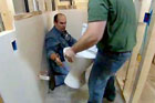 Richard Trethewey being handed a new toilet to install