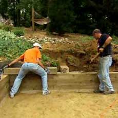 Roger Cook and homeowner putting some finishing touches on a timber retaining wall