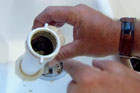 a clogged T-fitting from underneath a kitchen sink
