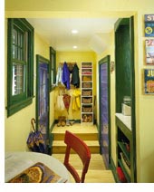 Even a cramped entry hall can benefit from basic storage ideas. In this backdoor entry, a tall, narrow bookcase makes the most of vertical space. Two tiers of clothing pegs double the hanging capacity of the wall.